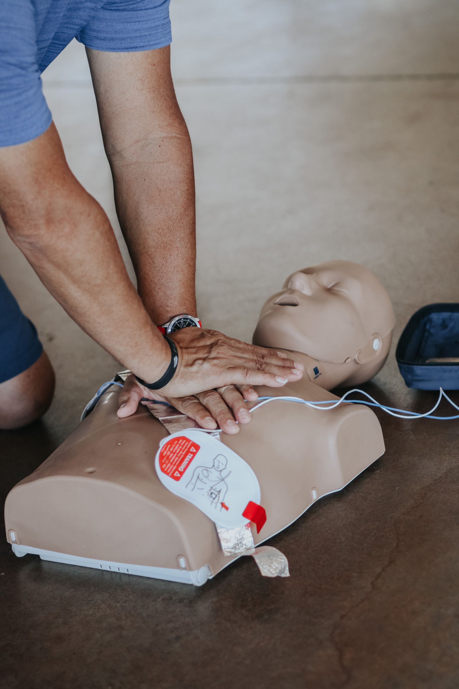 Nahaufnahme: Herzdruckmassage an einer Trainingspuppe mit AED während der 4h Kompakt-Auffrischung